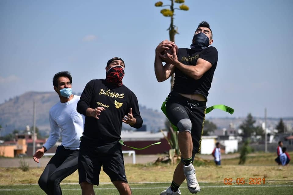 Jugadores de Lobos y Búhos jugando en campo, partido de fútbol americano